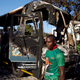 A supporter of the ruling ZANU-PF walks past a burnt vehicle at the party's offices a day after the clashes between security forces and opposition protesters in Harare, Zimbabwe, August 2, 2018.